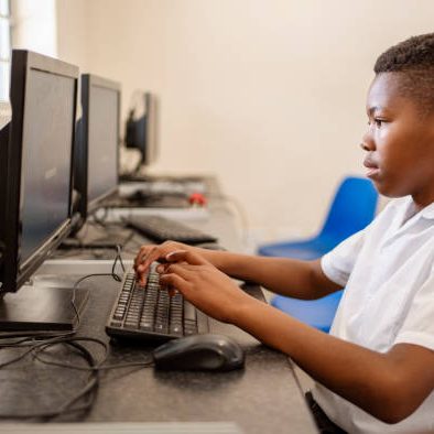 Side view of a schoolboy learning computer in class at primary school